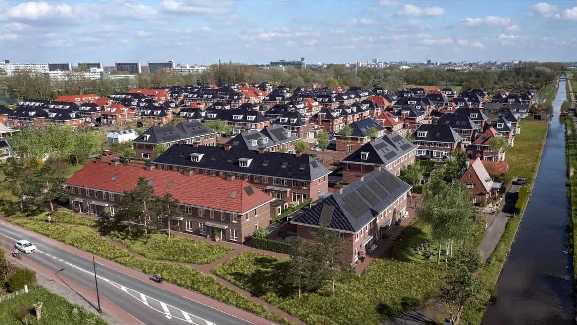 Villapark Eikelenburgh in Rijswijk, de woningen met rode en donkere pannendaken langs de vaart, met de stad aan de horizon